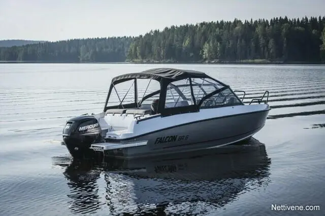 A white Falcon 56 boat with a black canopy is anchored on calm waters, surrounded by forested shoreline.